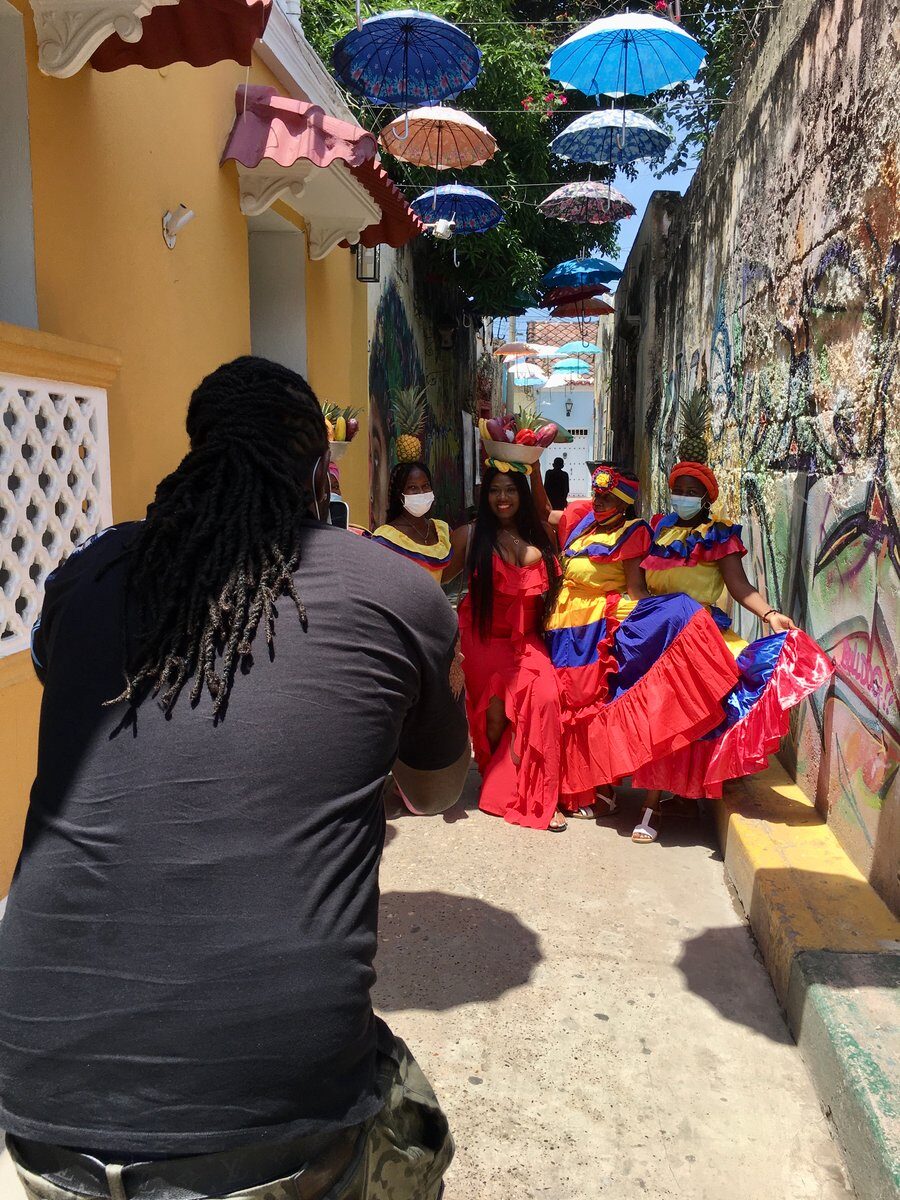 A photographer captures women in vibrant traditional dresses in a colorful street in Cartagena, Colombia.